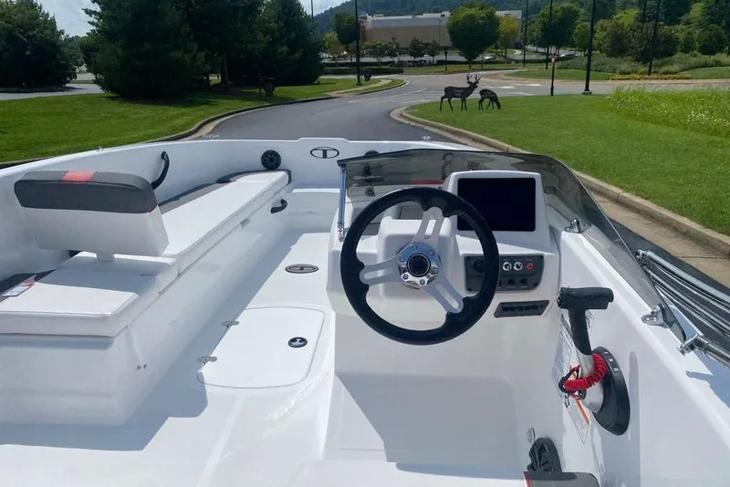 Slide: The Image of 2027 Tahoe T18 boat interior with steering wheel and seating, parked outdoors. - 5