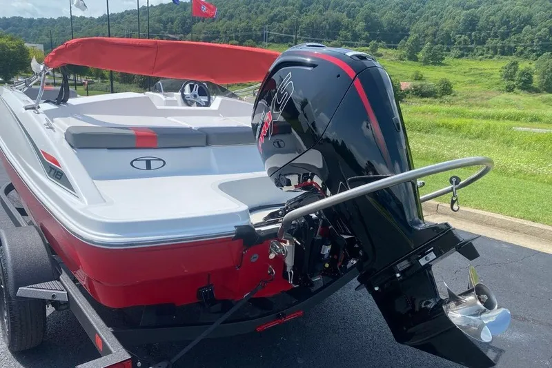 Slide: The Image of 2027 Tahoe T18 boat with outboard motor, red and white design, parked outdoors. - 2