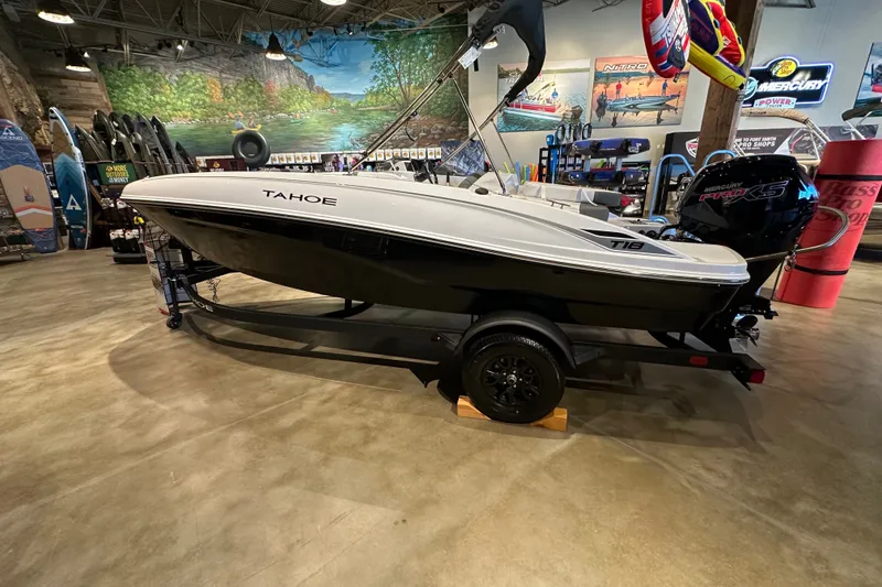 The Image of 2027 Tahoe T18 boat displayed indoors with Mercury engine, surrounded by water sports equipment. - 0