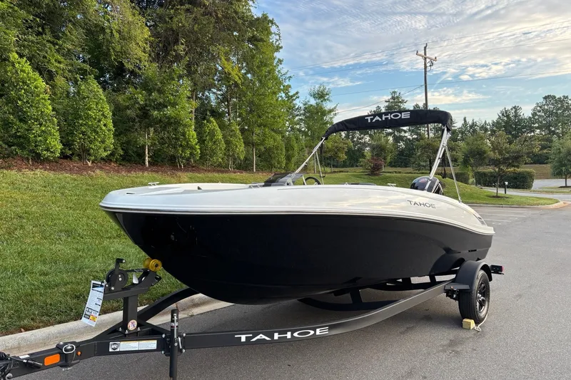 Slide: The Image of 2027 Tahoe T18 boat on trailer, parked on a road with lush greenery. - 2