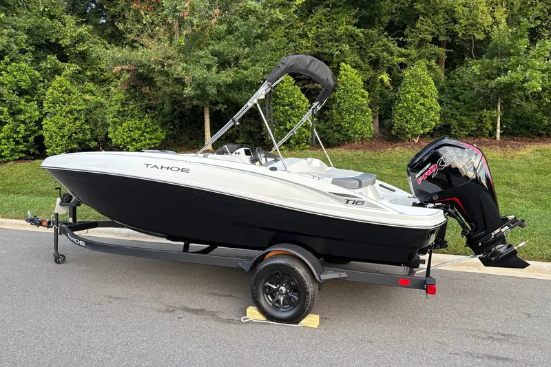 Slide: The Image of 2027 Tahoe T18 boat on trailer, parked on road with lush greenery background. - 4