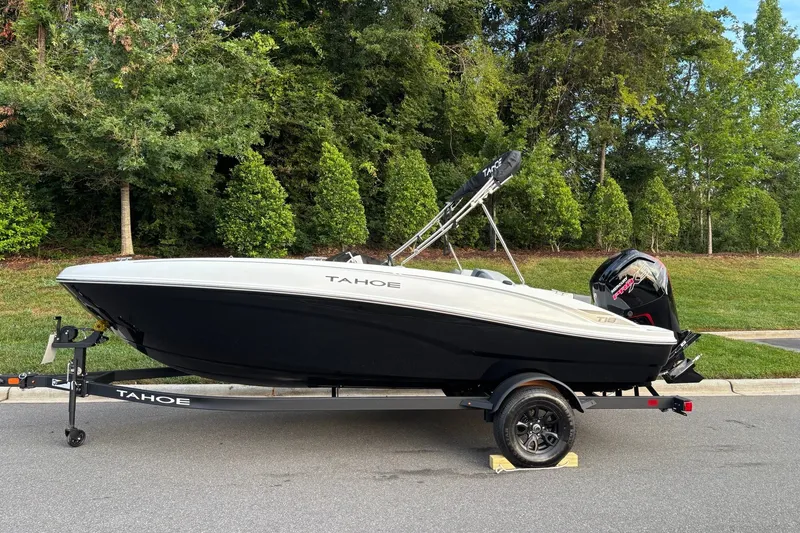 The Image of 2027 Tahoe T18 boat on trailer, parked on road with lush greenery background. - 0