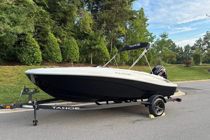 Slide: The Image of 2027 Tahoe T18 boat on trailer, parked outdoors with lush greenery background. - 1