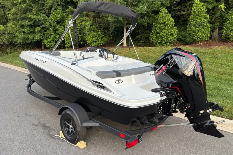 Slide: The Image of 2027 Tahoe T18 boat with Mercury engine on trailer, parked near lush greenery. - 5