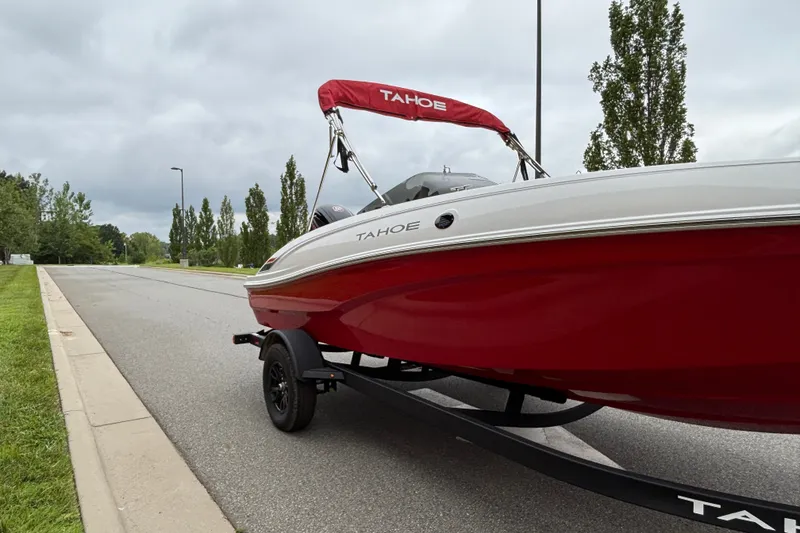 Slide: The Image of 2027 Tahoe T18 boat with red hull on trailer, parked on a suburban street. - 64
