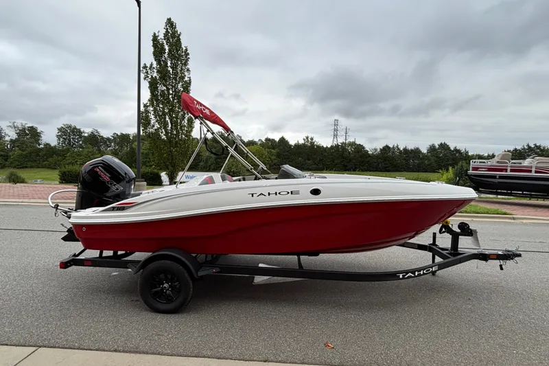 Slide: The Image of 2027 Tahoe T18 boat with red hull on trailer, parked outdoors. - 65