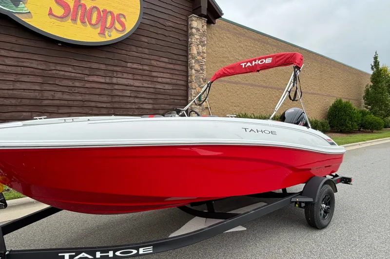 Slide: The Image of 2027 Tahoe T18 boat with red and white design on a trailer outside a shop. - 63