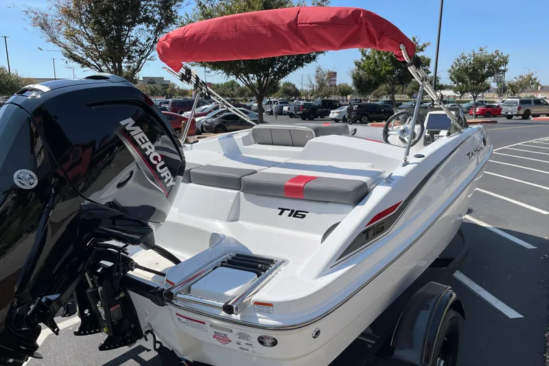 Slide: The Image of 2027 Tahoe T16 boat with Mercury engine, red canopy, parked in a lot. - 5