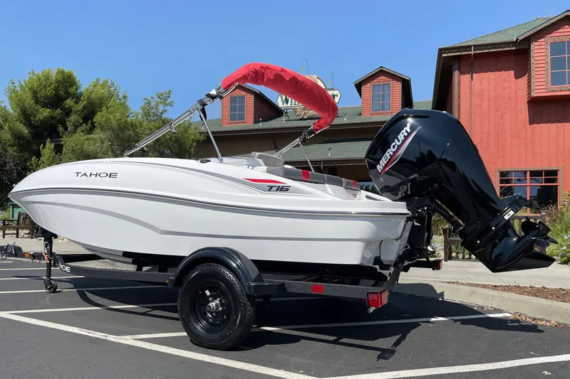Slide: The Image of 2027 Tahoe T16 boat with Mercury engine, parked outdoors near a rustic building. - 3
