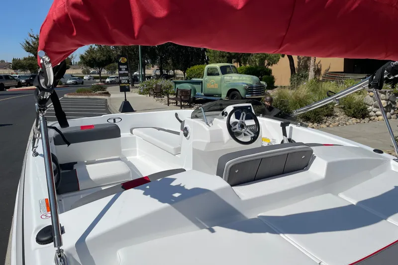 Slide: The Image of 2027 Tahoe T16 boat with red canopy, parked outdoors in a sunny setting. - 6
