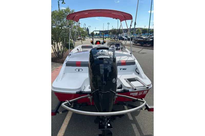 Slide: The Image of 2027 Tahoe T16 boat with outboard motor and red canopy, parked outdoors. - 2