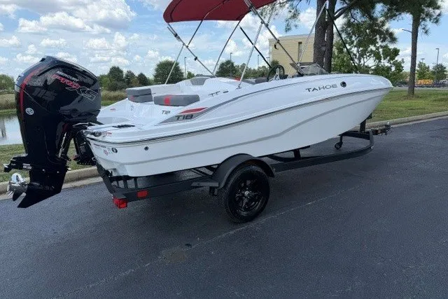 Slide: The Image of 2027 Tahoe T18 boat on trailer with outboard motor, parked outdoors under a red canopy. - 1
