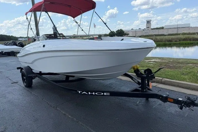 Slide: The Image of 2027 Tahoe T18 boat with red canopy on trailer, parked near water. - 2