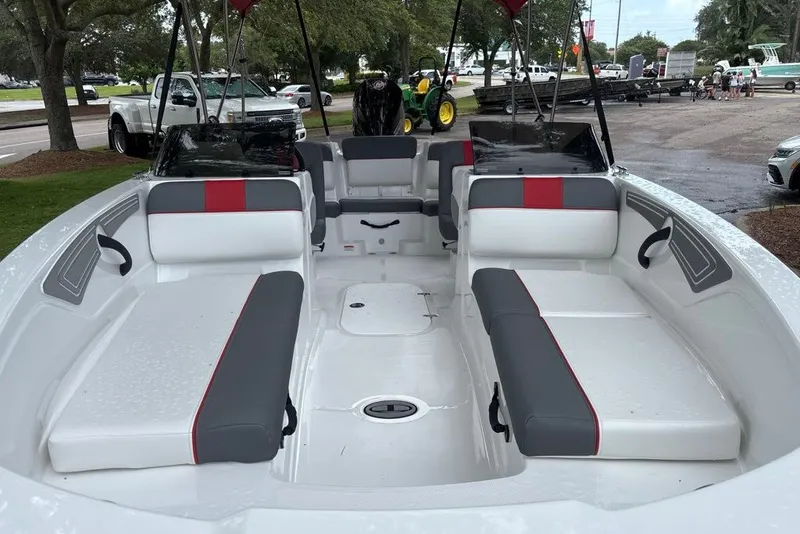 Slide: The Image of 2027 Tahoe T21 boat interior with gray and red seating, parked outdoors. - 1