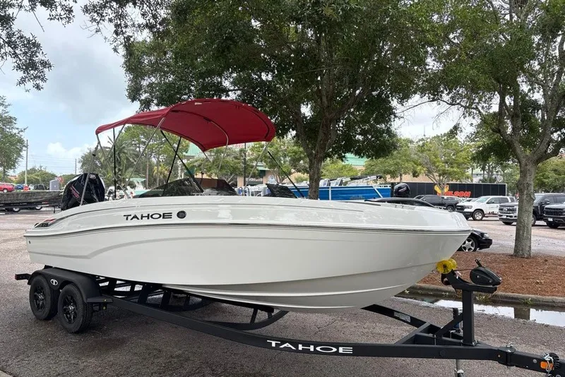 Slide: The Image of 2027 Tahoe T21 boat with red canopy on trailer, parked outdoors. - 7