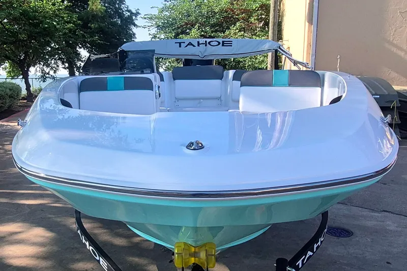 Slide: The Image of 2027 Tahoe T16 boat with sleek white and turquoise design, parked outdoors. - 2
