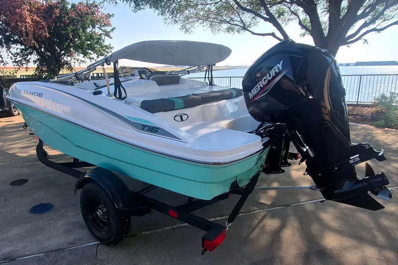 Slide: The Image of 2027 Tahoe T16 boat with Mercury engine, parked near a waterfront under trees. - 7