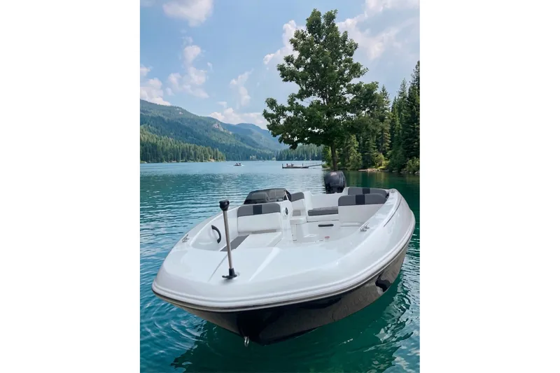 The Image of 2027 Tahoe T18 boat on a serene lake with forested mountains in the background. - 1