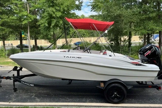 Slide: The Image of 2027 Tahoe T18 boat with red canopy on trailer, parked outdoors. - 1