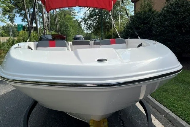 Slide: The Image of 2027 Tahoe T18 boat with red canopy, parked on a sunny street. - 2