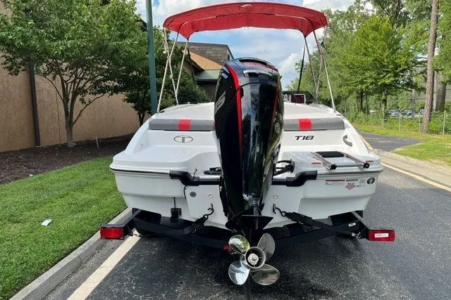 Slide: The Image of 2027 Tahoe T18 boat with outboard motor, parked on a paved road, surrounded by greenery. - 3