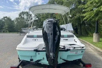 Slide: The Image of 2027 Tahoe T16 boat with outboard motor, parked on a trailer in a scenic area. - 2