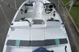 Slide: The Image of 2027 Tahoe T16 boat interior with seating and steering wheel, parked on pavement. - 5
