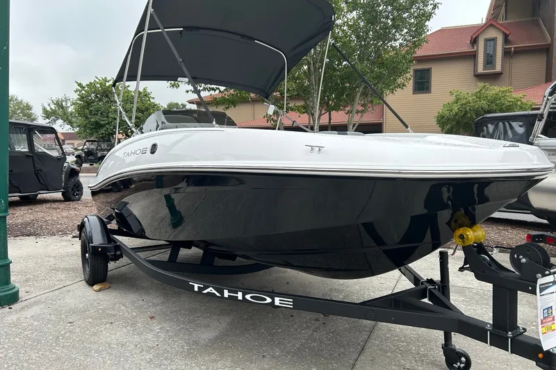 The Image of 2027 Tahoe T16 boat on trailer with canopy, parked outdoors near buildings. - 0