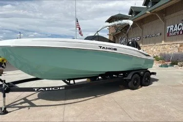 The Image of 2027 Tahoe T21 boat on trailer outside dealership with American flag. - 0