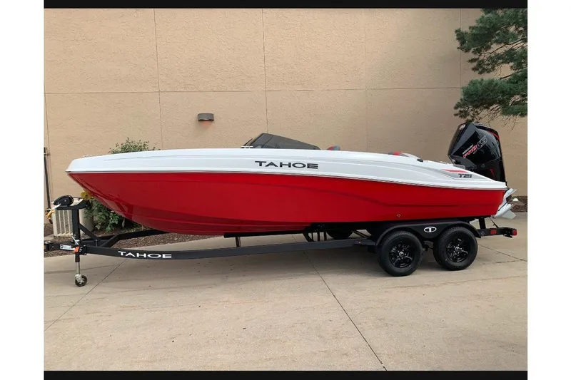 The Image of Red and white 2027 Tahoe T21 boat on trailer, parked outdoors. - 0