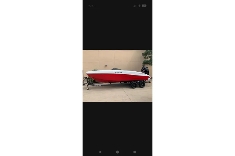 The Image of Red and white 2027 Tahoe T21 boat on trailer, parked outdoors. - 0