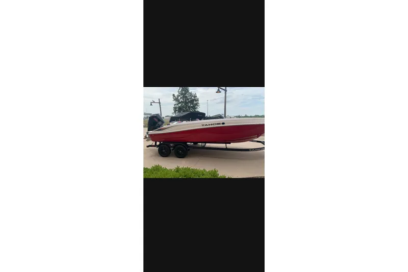Slide: The Image of Red 2027 Tahoe T21 boat on trailer, parked outdoors. - 2