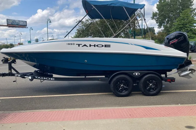 Slide: The Image of 2027 Tahoe 1950 boat on trailer, blue and white design, parked outdoors. - 1