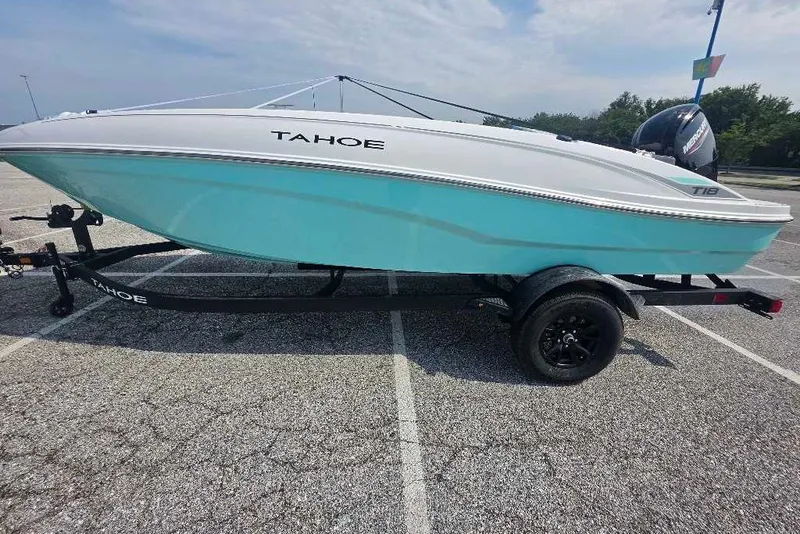 The Image of 2027 Tahoe T18 boat on trailer, turquoise hull, parked in lot under cloudy sky. - 0