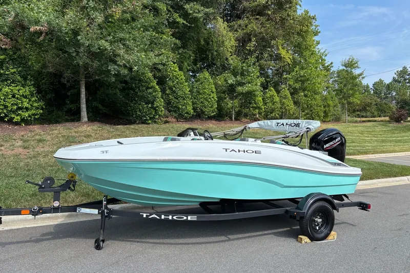 Slide: The Image of 2027 Tahoe T16 boat on trailer, parked outdoors with lush greenery background. - 1