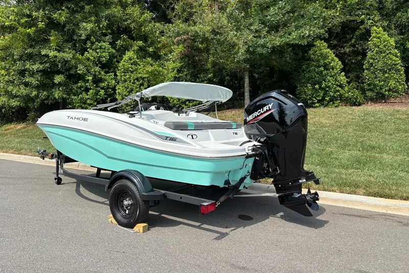 Slide: The Image of 2027 Tahoe T16 boat with Mercury engine on trailer, parked near lush greenery. - 4