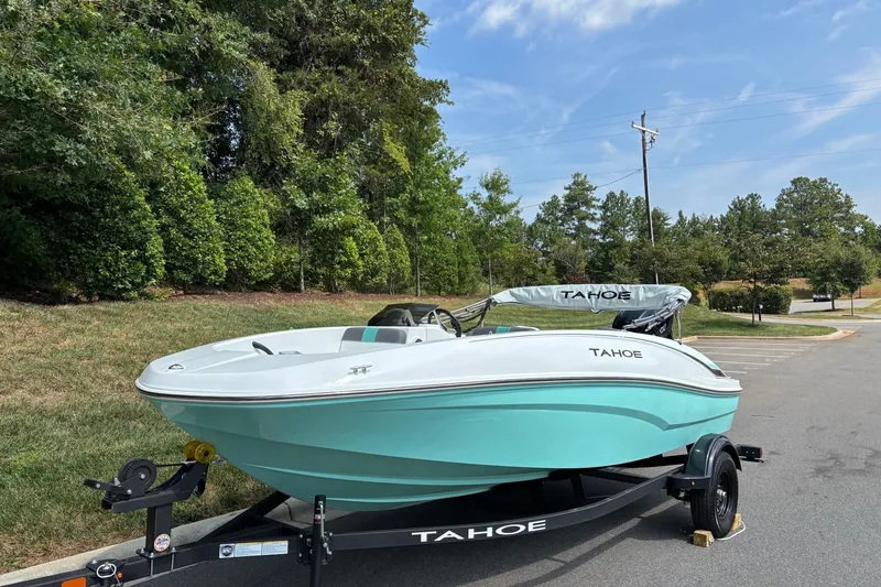 Slide: The Image of 2027 Tahoe T16 boat on trailer, parked outdoors with trees in background. - 2