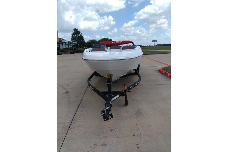 Slide: The Image of 2027 Tahoe T18 boat on trailer, parked on concrete under a cloudy sky. - 2