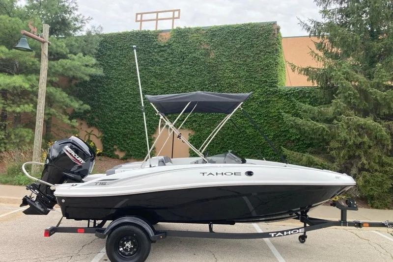 Slide: The Image of 2027 Tahoe T16 boat on trailer, parked outdoors with greenery background. - 1