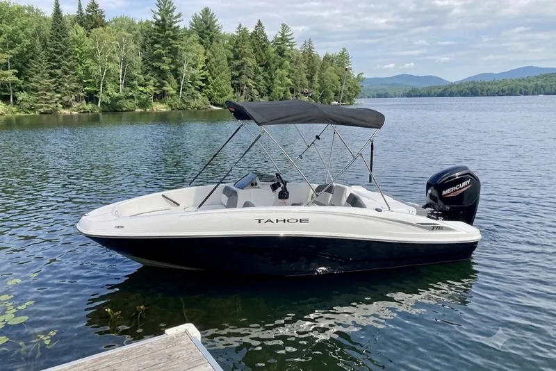The Image of 2027 Tahoe T16 boat on a serene lake with lush forest background. - 0