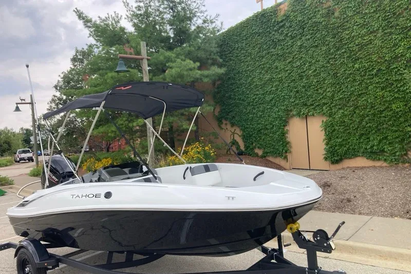 Slide: The Image of 2027 Tahoe T16 boat with canopy on trailer, parked near ivy-covered wall. - 3
