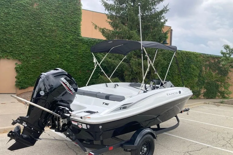 Slide: The Image of 2027 Tahoe T16 boat with Mercury engine, parked outdoors, featuring sleek design and canopy. - 7