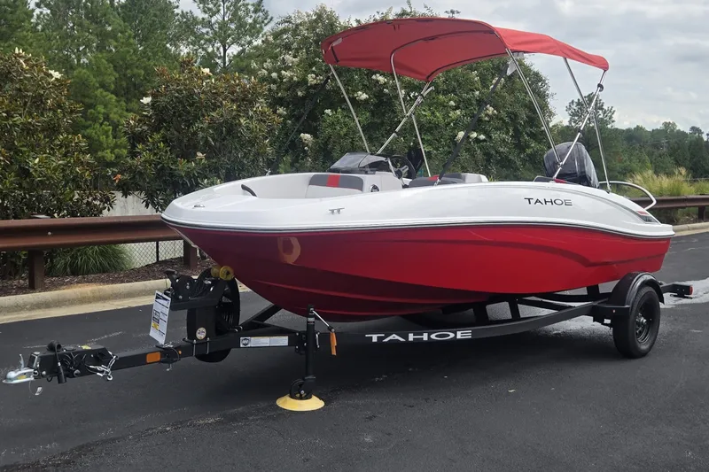 Slide: The Image of 2027 Tahoe T16 boat with red canopy on trailer, parked outdoors. - 5