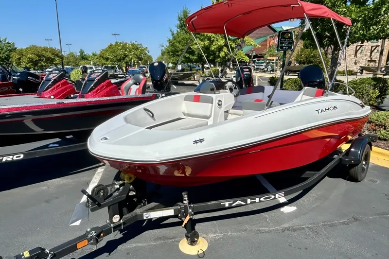 The Image of 2027 Tahoe T16 boat with red hull and canopy on a trailer in a parking lot. - 0
