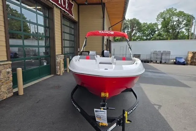 Slide: The Image of 2027 Tahoe T18 boat with red hull on trailer, parked outside a building. - 1