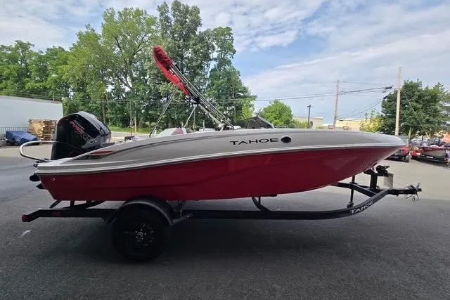 Slide: The Image of 2027 Tahoe T18 boat with red hull on trailer, parked outdoors. - 3