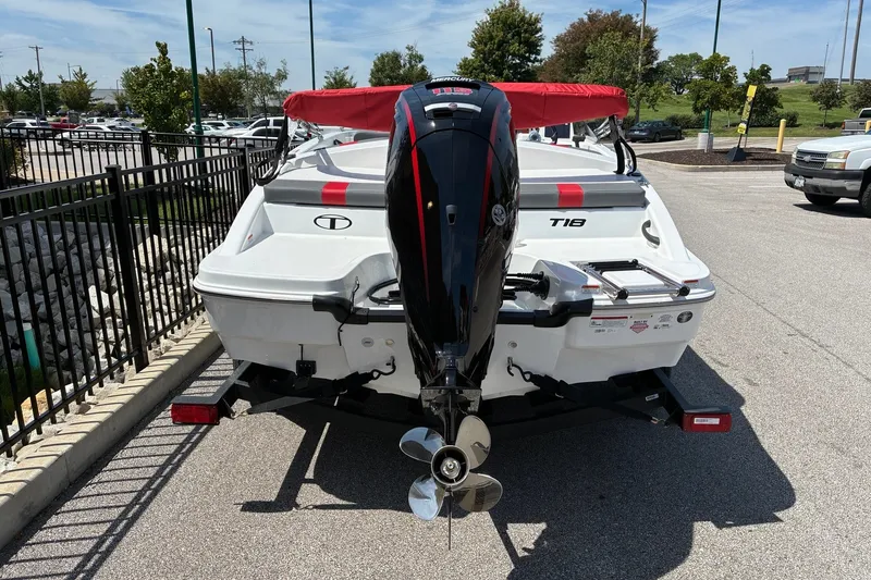 Slide: The Image of 2027 Tahoe T18 boat with outboard motor, parked on a trailer in a lot. - 2