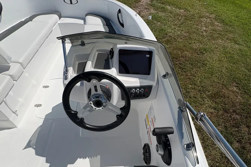 Slide: The Image of 2027 Tahoe T16 boat interior with steering wheel and seating on grassy area. - 17