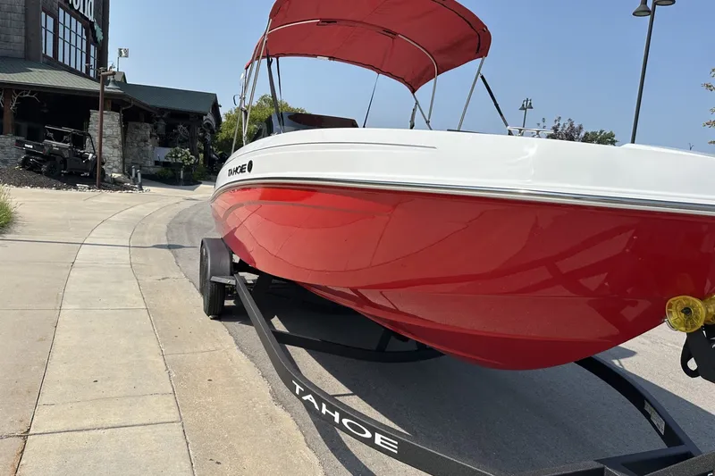 Slide: The Image of Red 2027 Tahoe T21 boat on trailer, parked near a building. - 8