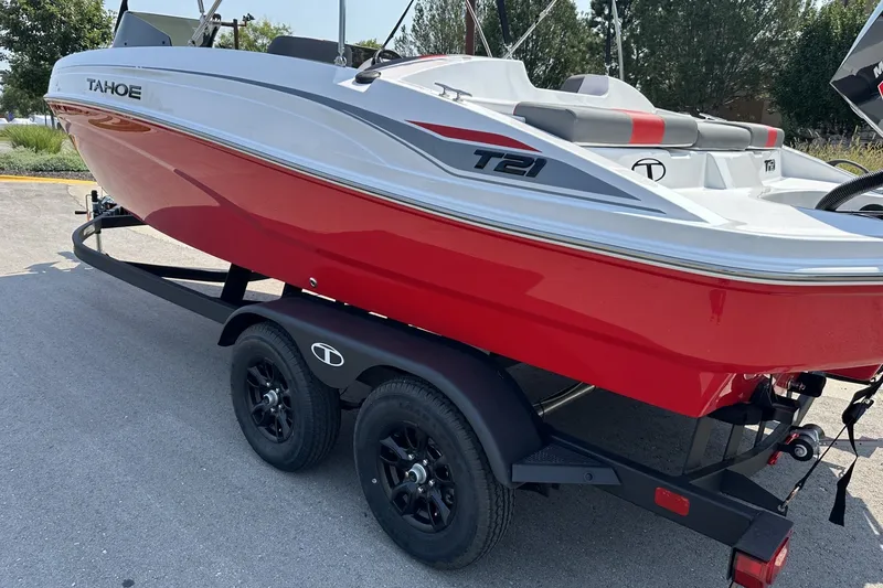 Slide: The Image of Red 2027 Tahoe T21 boat on trailer, parked outdoors, showcasing sleek design and modern features. - 2